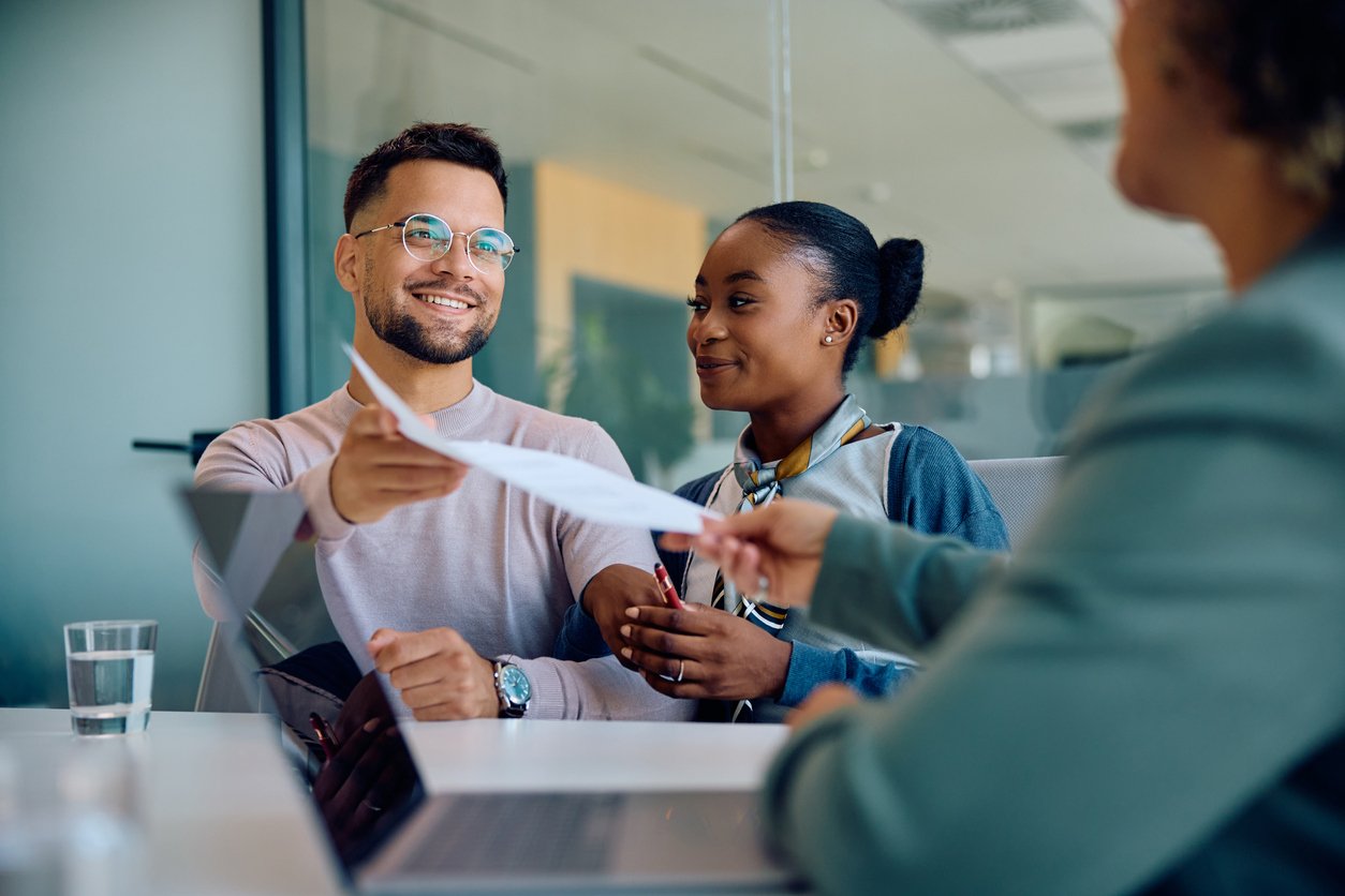 image of loan officer handing documents to her clients