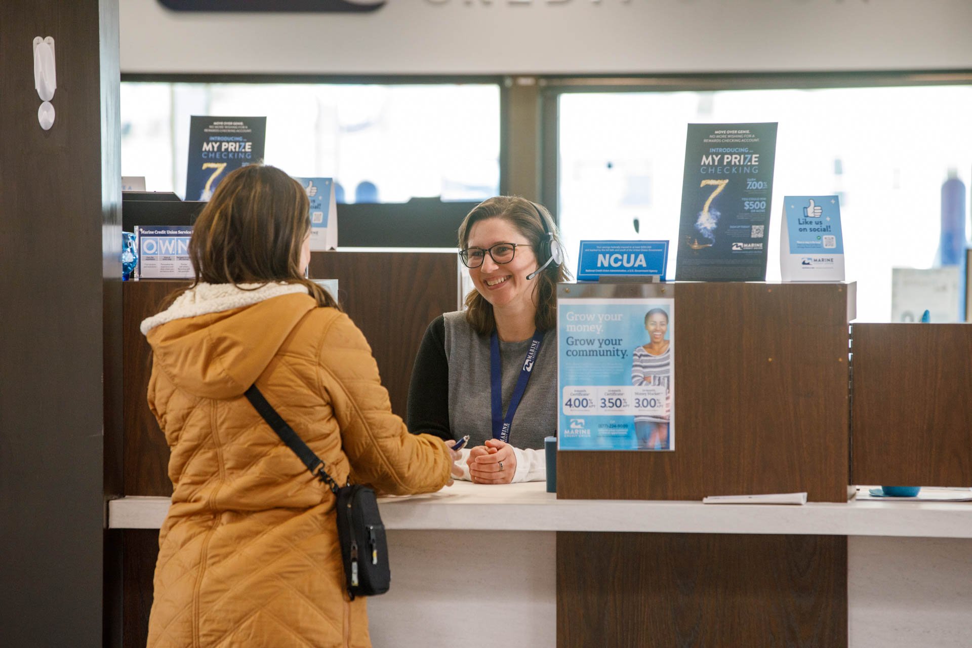 an image of a bank teller helping a customer at the front counter while they smile and chat