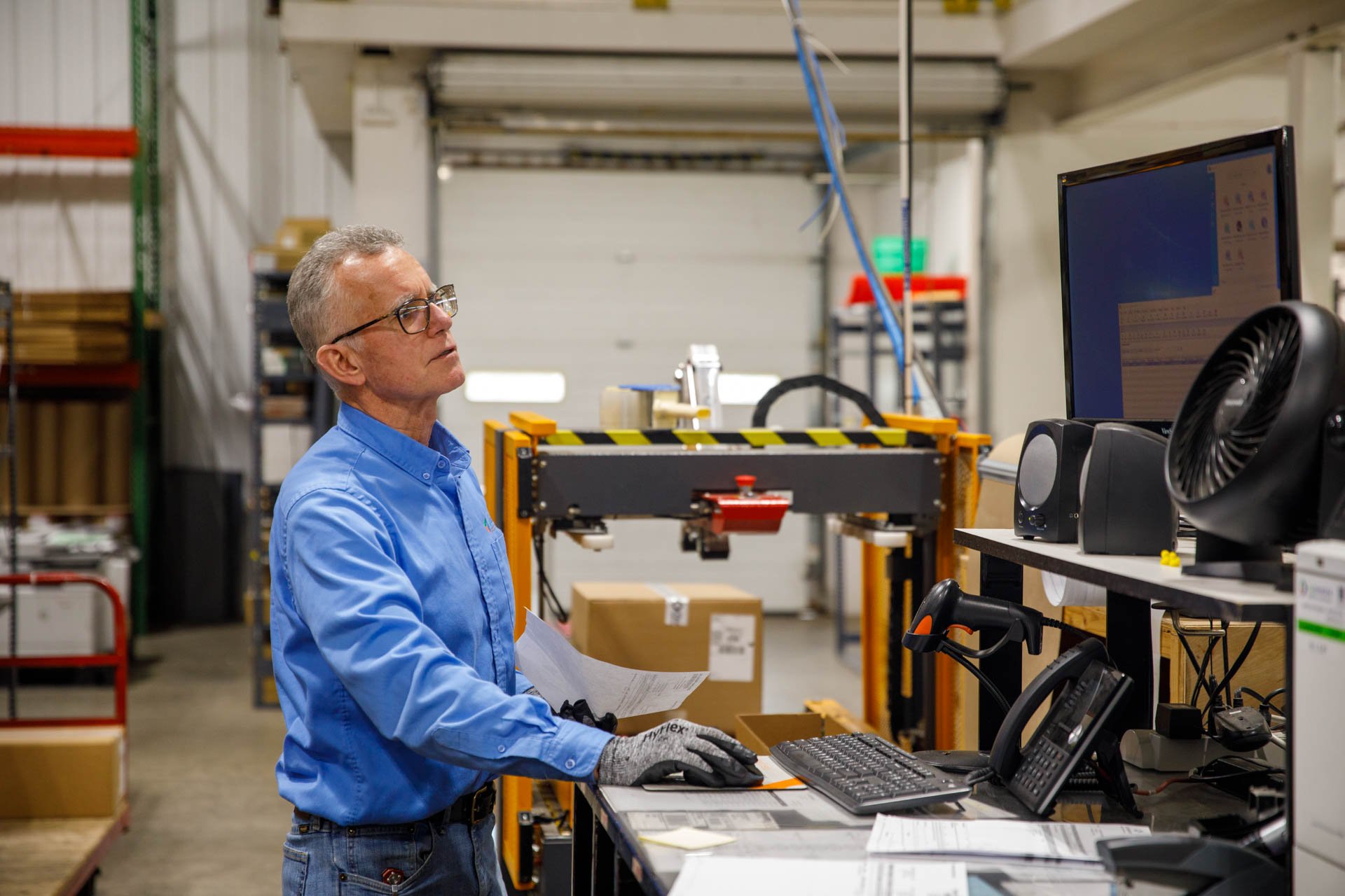 an image of a warehouse employee entering data from a packing slip into a computer