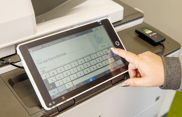 an image of a person using secure document scanning through papercut on a multifunction device.