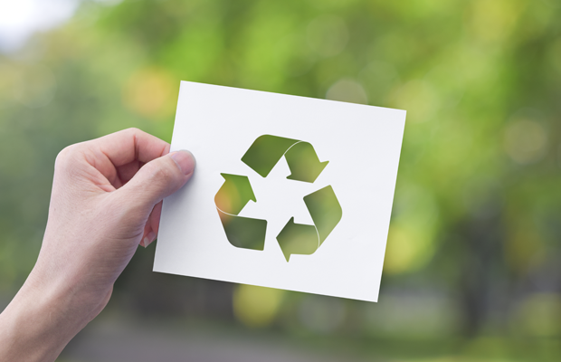an image of a person holding a piece of paper with the universal recycling symbol on it.